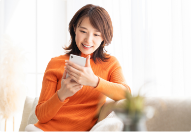 自宅でスマホを使ってメールをしている女性